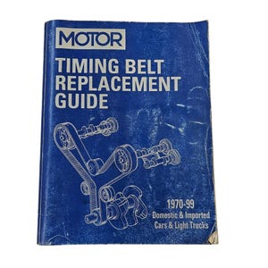 Puede incluir: Un libro azul titulado "MOTOR TIMING BELT REPLACEMENT GUIDE" con un diagrama de un sistema de correa de distribución. El libro cubre automóviles y camionetas ligeras nacionales e importadas de 1970 a 1999.