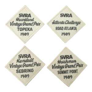 May include: Four vintage SVRA racing patches. Each diamond-shaped patch features text indicating the race name, location, and year 1989. The locations include Topeka, Road Atlanta, Sebring, and Summit Point. The patches are cream-colored with black text.
