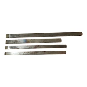 May include: A set of four flat metal bars of varying lengths, each featuring a beveled edge at one end. The metallic surfaces exhibit signs of oxidation and surface rust, with a dull grey finish and some slight discoloration along the edges.