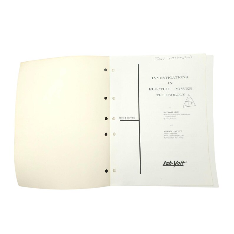 May include: An open book with the title "Investigations in Electric Power Technology" is displayed. The book has a black vertical line and a triangle symbol. The text "Lab-Volt" is printed at the bottom.