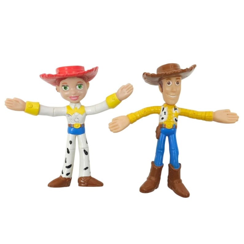 May include: Two articulated Toy Story character figures, Jessie and Woody. Jessie wears a red hat, white shirt, and cow-print trousers. Woody wears a brown hat, yellow shirt, and blue trousers. Both figures have outstretched arms.