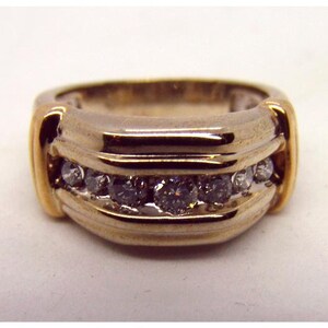 May include: A gold and silver band ring with a row of small diamonds set in the center.
