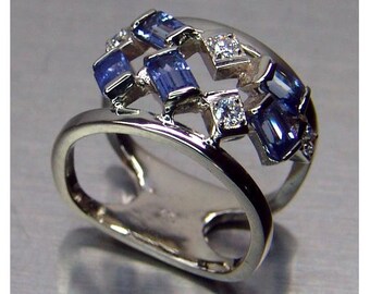 Ladies custom free form designed 14 karat white gold heat treated top Montana VS blue emerald cut sapphire and round diamond  dinner ring
