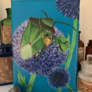 May include: A painting of a green insect on a blue background with purple flowers. The insect has a yellow spot on its back and is perched on a flower.