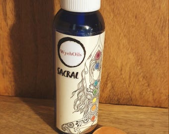 Puede incluir: Una botella de vidrio azul con un pulverizador blanco y una etiqueta que dice "WyehOils" y "Sacral". La etiqueta también presenta un dibujo de una mujer con un sistema de chakras de colores arcoíris. Una pequeña tarjeta marrón con las palabras "Sacral", "Neroli", "Ylang Ylang", "Clary Sage" y "Moonstone" está al lado de una piedra de luna naranja claro.