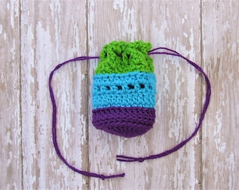 Puede incluir: Una pequeña bolsa de cordón de ganchillo con un diseño a rayas verde, azul y morado. La bolsa tiene un cordón morado.