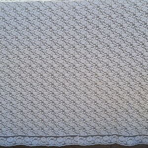 May include: White lace tablecloth with a floral pattern. The tablecloth has a scalloped edge.