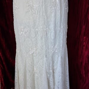 Puede incluir: Vestido de novia de encaje marfil con adornos florales y silueta de sirena. El vestido presenta delicados detalles de encaje y acentos brillantes, creando un look elegante y rom&aacute;ntico. La espalda tiene cierre de cremallera.