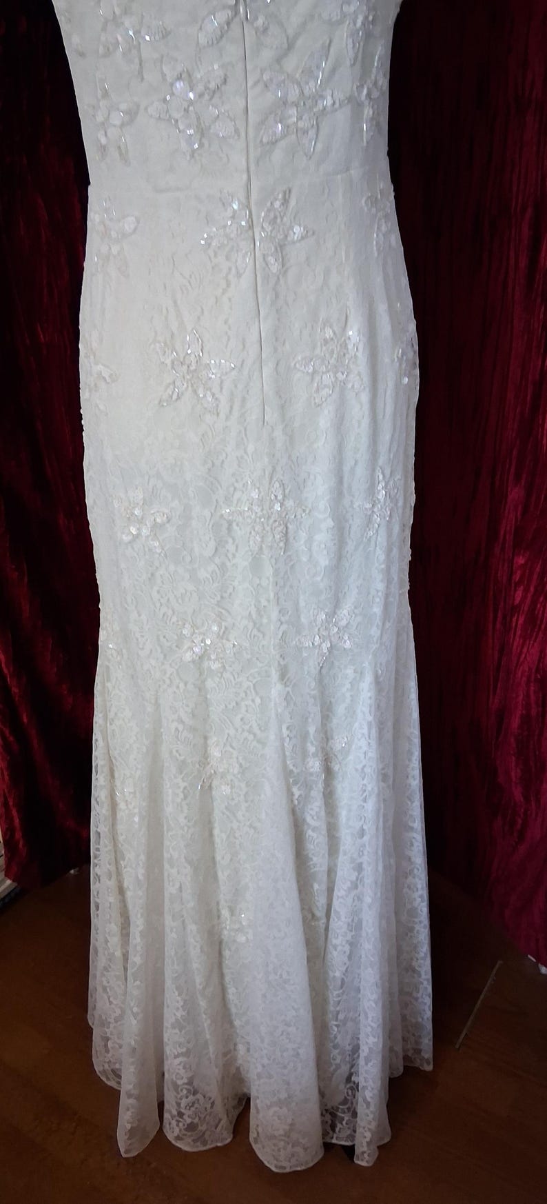 Puede incluir: Vestido de novia de encaje marfil con adornos florales y silueta de sirena. El vestido presenta delicados detalles de encaje y acentos brillantes, creando un look elegante y rom&aacute;ntico. La espalda tiene cierre de cremallera.