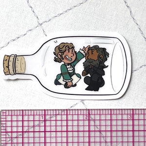 May include: A white glass bottle with a cork stopper, containing two cartoon figures. One figure is a man with brown hair and a green and white outfit, the other is a man with brown hair and a black outfit. The figures are looking at each other.