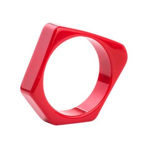 May include: A bright red plastic bangle bracelet with a geometric shape.