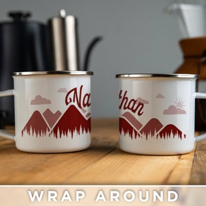 May include: Two white enamel mugs with a red mountain scene and the names "Nathan" and "Natalie" printed on them. The mugs are on a wooden surface.