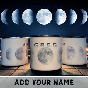 May include: Three white enamel mugs with black lettering and a moon phase design. The mugs are on a wooden surface. The text on the mugs reads "Greg", "Addison", and "K".