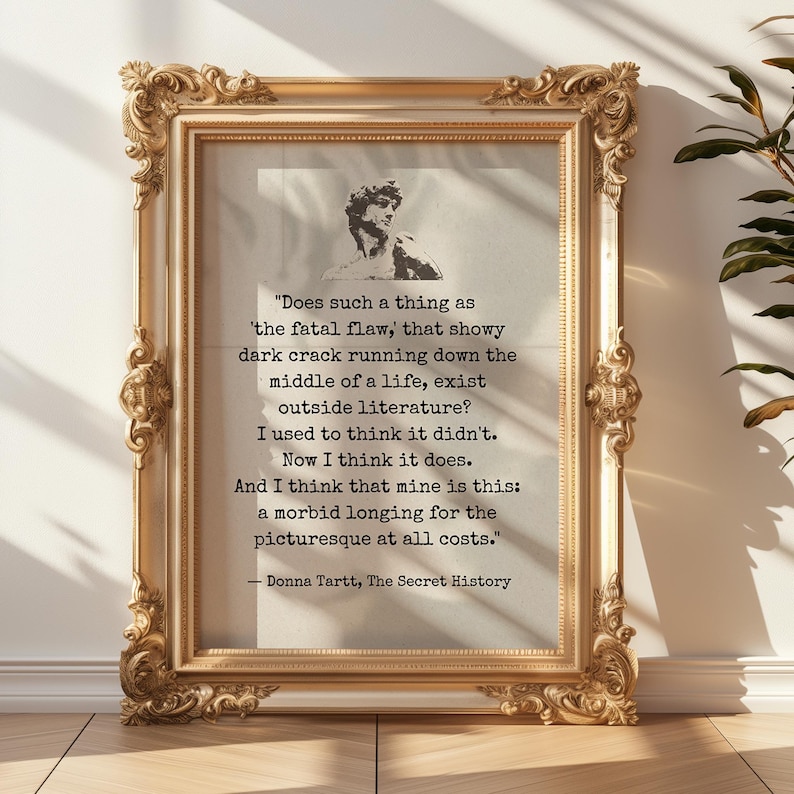 May include: A framed print with a gold ornate frame. The print features a quote from Donna Tartt's "The Secret History" with a bust image. The quote is in black text on a light background.