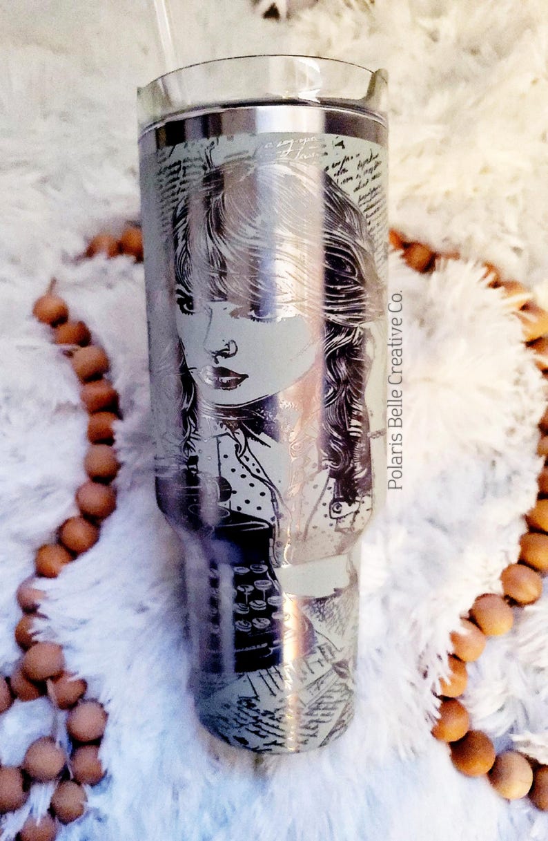 Puede incluir: Vaso de acero inoxidable con un retrato grabado de una mujer. El retrato est&aacute; rodeado de escritura y elementos de dise&ntilde;o. El vaso tiene una pajita transparente y las palabras "Polaris Belle Creative Co." est&aacute;n impresas en el lateral.