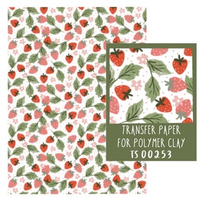 Peut inclure: Une feuille de papier transfert pour pâte polymère avec un motif répété de fraises rouges, de feuilles vertes et de fleurs roses. Le texte "TRANSFER PAPER FOR POLYMER CLAY TS 00253" est imprimé sur la feuille.