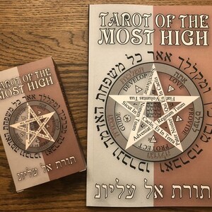 Puede incluir: Una baraja de tarot y una gu&iacute;a con el t&iacute;tulo "Tarot of the Most High" en ingl&eacute;s y hebreo. La gu&iacute;a presenta una gran estrella de seis puntas con texto hebreo y palabras en ingl&eacute;s alrededor de la estrella.