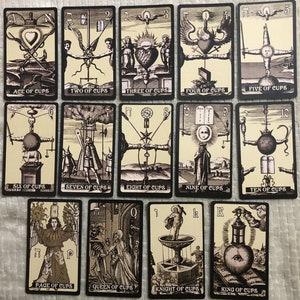 May include: Tarot card deck featuring the Cups suit. The cards are black with a cream background and feature detailed illustrations in black and white. The cards are numbered 1 through 10 and include the Page, Knight, Queen, and King of Cups.