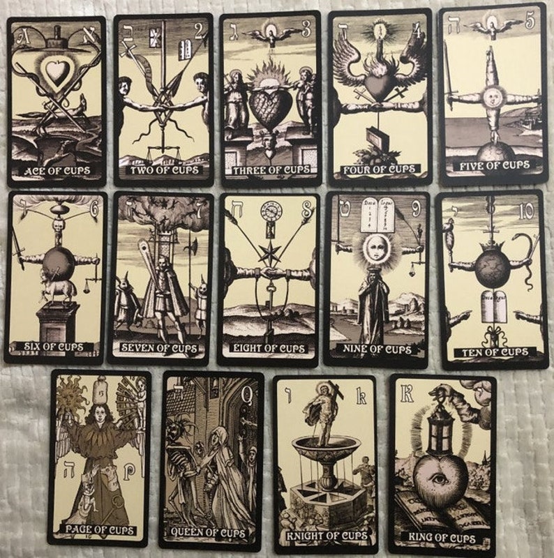 May include: Tarot card deck featuring the Cups suit. The cards are black with a cream background and feature detailed illustrations in black and white. The cards are numbered 1 through 10 and include the Page, Knight, Queen, and King of Cups.