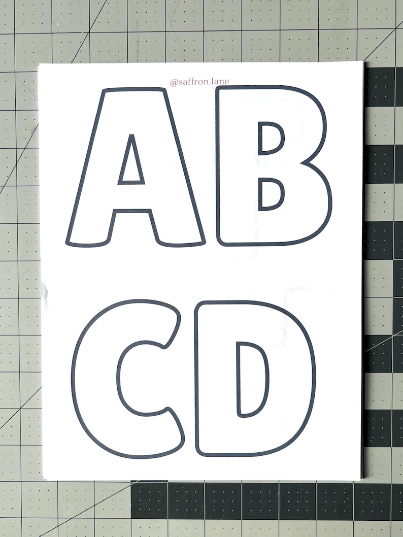 May include: White rectangular sticker sheet with the letters A, B, C, and D in a dark gray outline font. The letters are in a bold, rounded style. The text "@saffron.lane" is in the upper right corner.