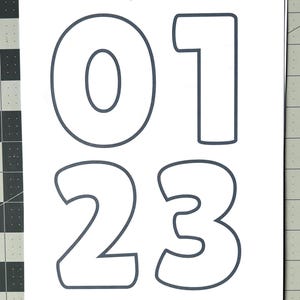 May include: White paper with the numbers 0, 1, 2, and 3 outlined in dark gray. The numbers are in a bold, rounded font. The text "@saffron.lane" is in the top right corner.
