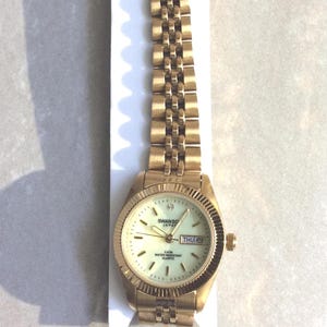SWANSON Damenuhr Rund Glow in the Dark Zifferblatt Gold Index Stunden Tag & Datum auf einem Gold Linked Band Neue Unbenutzte Vintage Uhr WR5ATM bewertet!