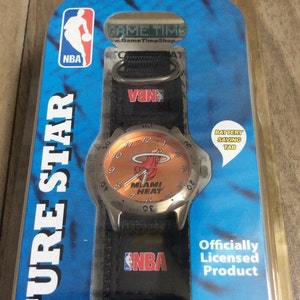 May include: A Miami Heat watch with a black strap and a silver watch face. The watch face is orange with the Miami Heat logo and the NBA logo. The packaging includes the NBA logo and the words "Future Star".
