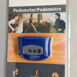 May include: A blue Timex pedometer in its original packaging. The pedometer has a digital display and three buttons. The packaging includes images of people exercising and text that reads "Counts Steps" and "Tracks Distance."