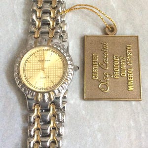 Reloj de vestir para hombre Oleg Cassini, esfera redonda con detalles dorados, índices de horas en correa de eslabones de dos tonos, reloj nuevo vintage sin usar.