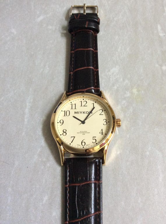 Reloj MIYKON dorado para hombre esfera redonda beige horas numeradas en negro sobre una correa de cuero negro cereza articulo vintage nuevo sin
