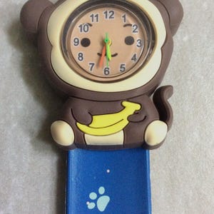 Reloj infantil con forma de mono: esfera marrón, correa azul ajustable, estilo vintage.