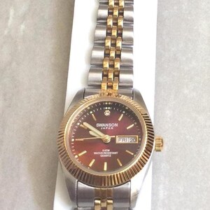 SWANSON Zweifarbige Damenuhr Rund Rot Datum Zifferblatt Gold Index Stundenmarkierer auf einem zweifarbigen Armband Link Neue Unbenutzte Vintage Uhr!