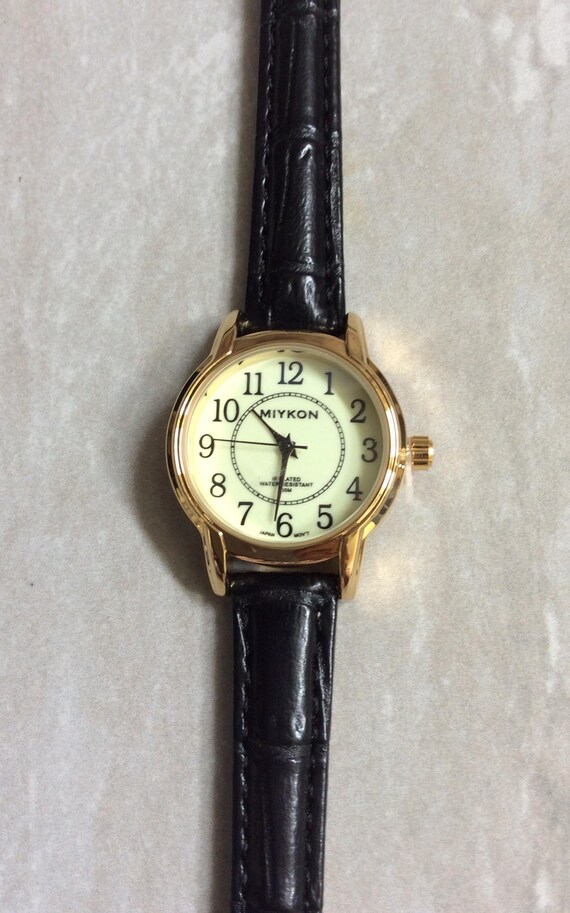 MIYKON Gold Women's Watch Round Glow in the Dark Dial Black Numbered Hours, all on a Black leather Band WR Rated 30m New Unused Vintage!
