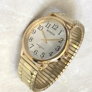 Reloj MIYKON para hombre con correa elástica dorada y esfera plateada redonda. Las horas numeradas en negro proporcionan una fácil lectura de la hora. ¡Reloj vintage nuevo sin usar WR!