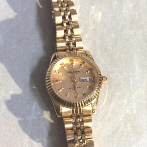 SWANSON Damenuhr Rundes goldenes Zifferblatt Einzigartige Stunden Marker Tag & Datum auf einem Gold Linked Band Neuer unbenutzter Vintage Artikel Wunderschöne Uhr!