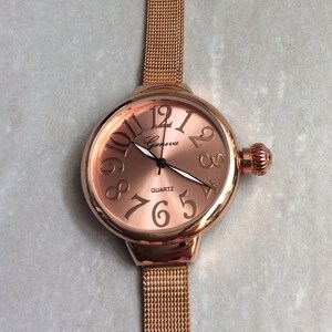 GENEVA Damen Roségold-Armbanduhr mit rundem Zifferblatt und nummerierten Stunden auf einem Roségold-Mesh-Band