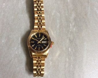 SWANSON Gold Women's Watch Round Black Dial Unique Gold Hour Markers Day & Date on a Gold Linked Band Unused New Vintage Item Awesome!