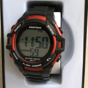 Könnte beinhalten: Schwarze und rote digitale Armitron Pro Sport-Uhr. Das Zifferblatt zeigt die Uhrzeit und Sekunden an. Zu den Funktionen gehören Wasserdichtigkeit bis 50,29 Meter, Alarm und Chronographenfunktionen. Die Uhr befindet sich in der Originalverpackung.