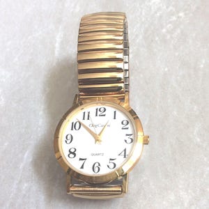 Oleg Cassini Gold Women's Watch Round White Dial with Easy to Read Black Arabic Numbered Hours Gold Stretch Band Vintage Mint Condition Rare