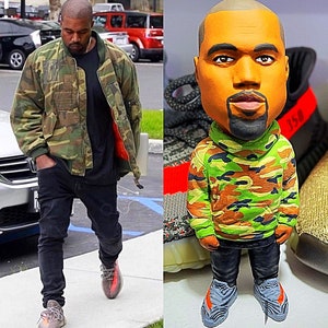 May include: A figurine of a person wearing a camouflage jacket and jeans. The figurine is standing on a pair of sneakers with the number 350 on them.