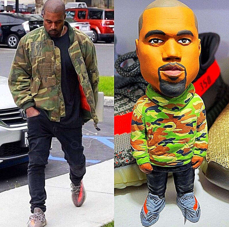 May include: A figurine of a person wearing a camouflage jacket and jeans. The figurine is standing on a pair of sneakers with the number 350 on them.