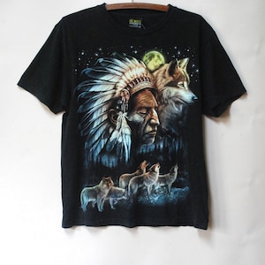 May include: Black t-shirt with a graphic print of a Native American chief wearing a headdress and a wolf howling at the moon. There are other wolves howling in the background.