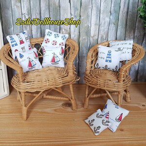 May include: Two miniature wicker chairs with cushions featuring nautical designs. The cushions have patterns of lighthouses, sailboats, anchors, and life preservers. The chairs are perfect for a dollhouse or miniature setting.