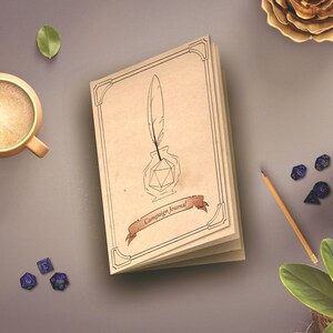 Pode incluir: Um di&aacute;rio de couro marrom com uma ilustra&ccedil;&atilde;o em preto e branco de uma pena e um tinteiro na capa. O di&aacute;rio est&aacute; aberto para revelar p&aacute;ginas em branco. O texto "Campaign Journal" est&aacute; impresso na capa.