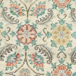 May include: Close-up of a beige rug with an intricate floral pattern. The design features orange, red, and green flowers, with black decorative elements. The rug has a vintage, traditional style, suitable for home decor.