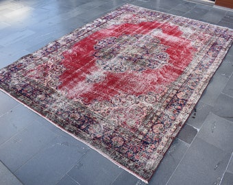 May include: A large, rectangular, distressed rug with a central red field and ornate, faded floral patterns. The border is dark blue and gray. The rug appears to be vintage or antique, with a worn appearance.