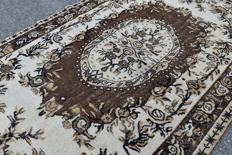 May include: A vintage rug with a brown and white floral pattern. The rug has a central medallion with a geometric design.