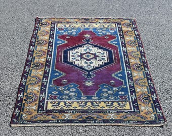 May include: A traditional Turkish rug with a colorful geometric pattern. The rug features a central medallion in shades of blue, red, and white, surrounded by a border of yellow and orange.