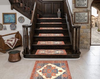 May include: A wooden staircase with patterned stair treads and a large area rug. The rug features a central diamond design in cream, blue, and orange. The staircase is dark wood with a decorative railing.