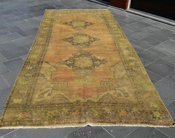 May include: A vintage rug with a faded orange and green color scheme. The rug has a traditional Persian design with intricate floral patterns.